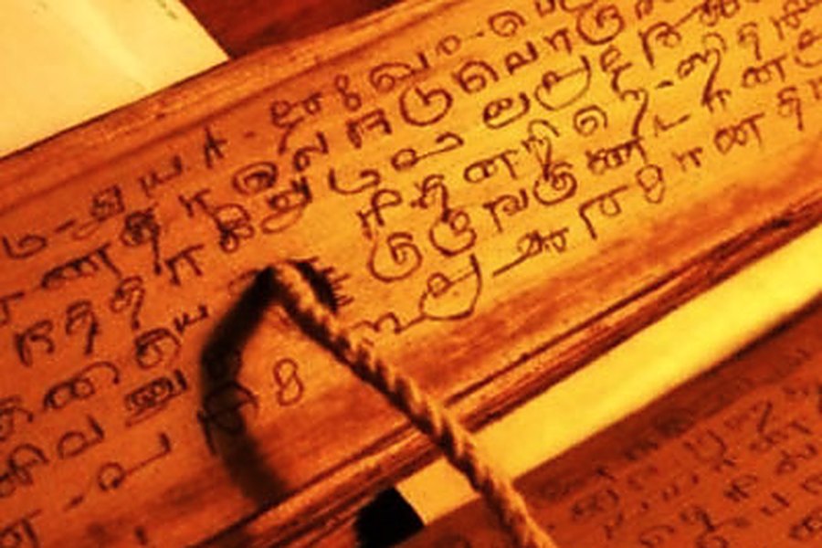 Old Tamil verse inscribed on a palm leaf, bound through the hole with a cord